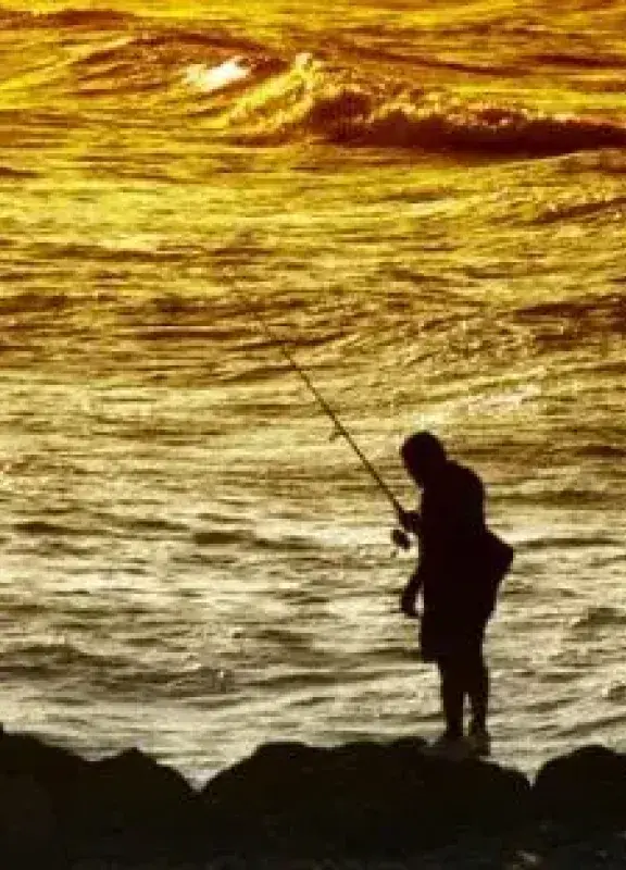 Pescador en la orilla del mar al atardecer Pescador en la orilla del mar al atardecer