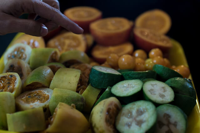 imagen de Maracuyá partida a la mitad y uchuvas con mano señalandola, frutas colombianas, recetas de jugos naturales
