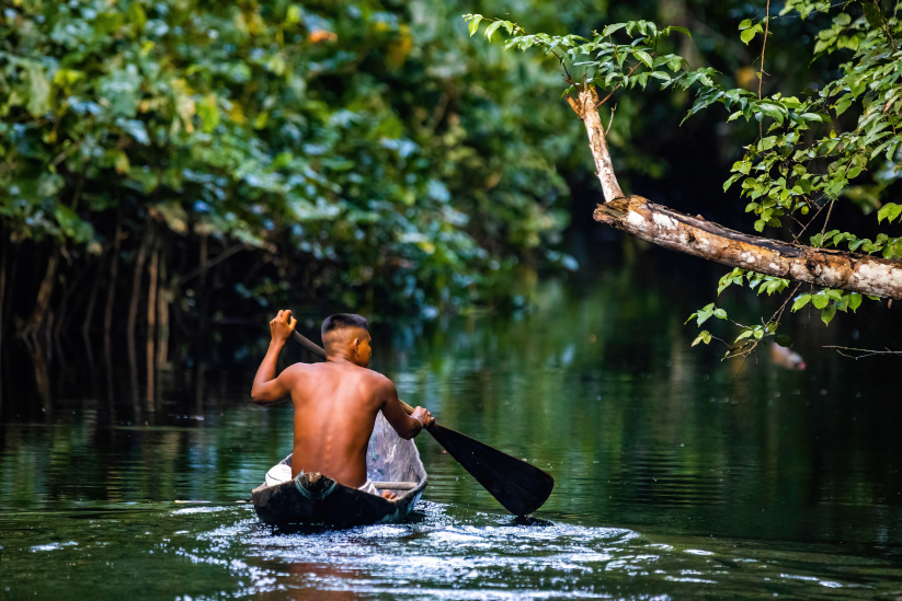 Hombre indígena navega el río Amazonas.