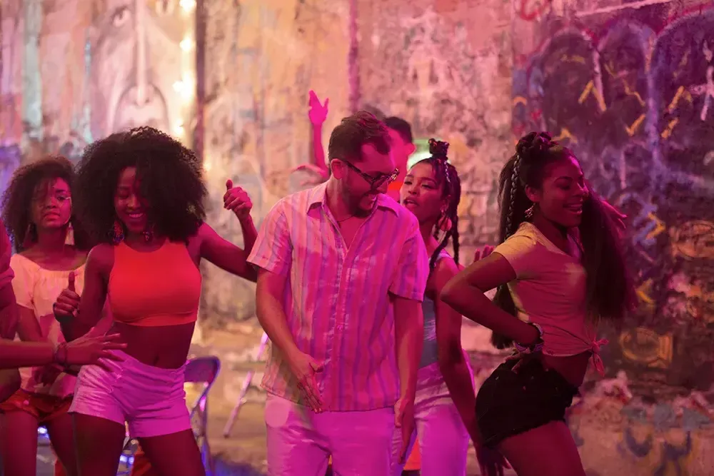 Jóvenes bailan en la calle bajo luces de neón en ambiente festivo