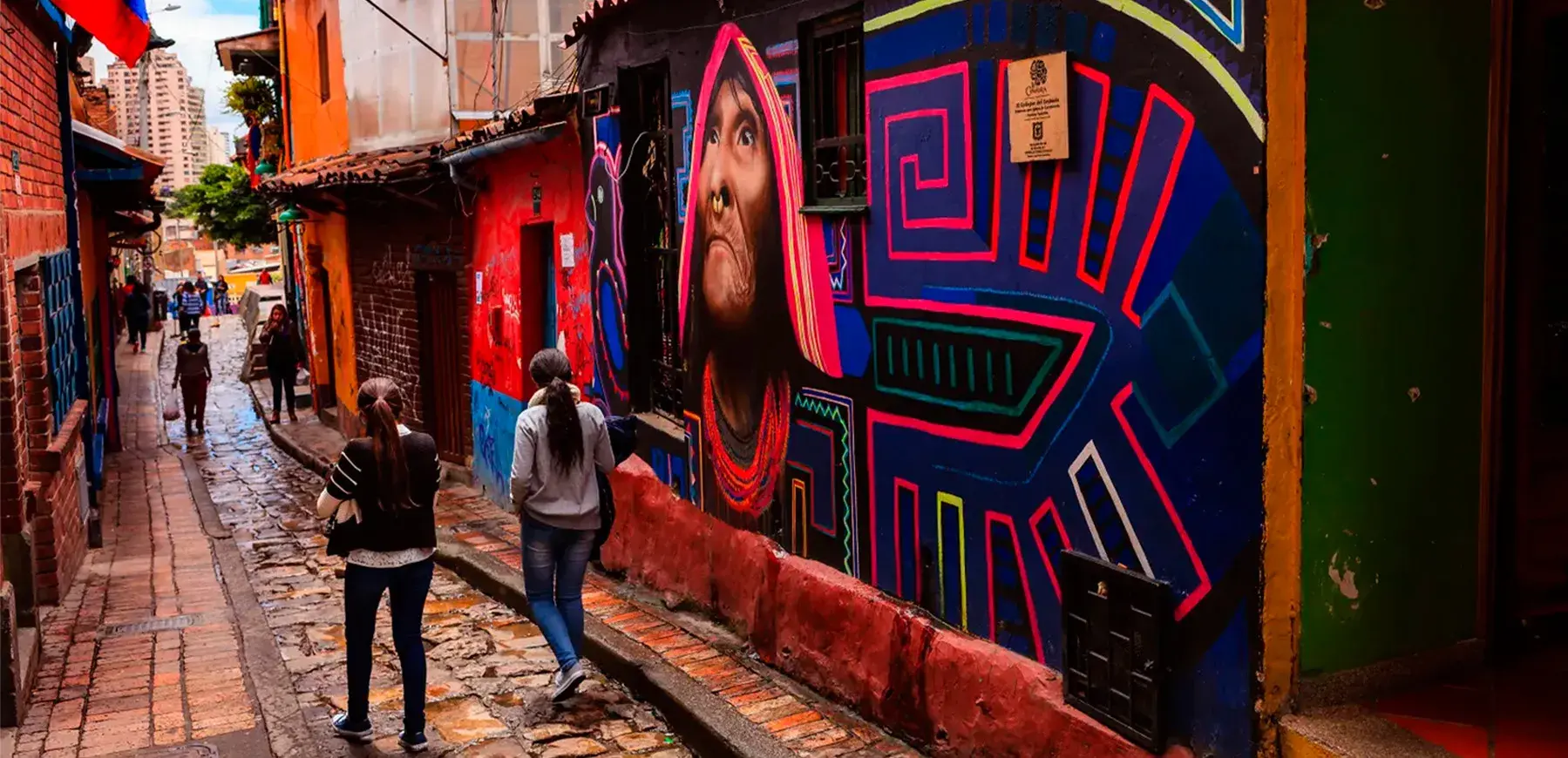 Callejón del Embudo in La Candelaria Bogotá, decorated with colorful murals and people walking