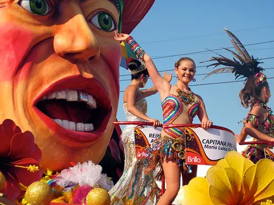 Festive float with a big mask and dancers at the Barranquilla Carnival.