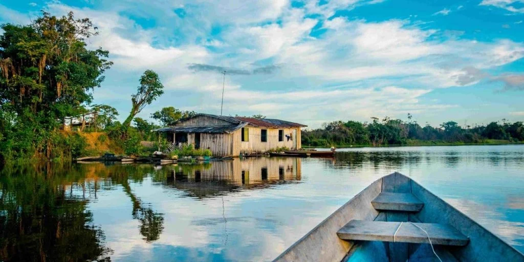 Casa de madera junto a un río en la selva con cielo azul