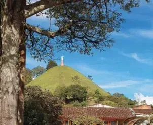 Colina verde con una cruz en la cima y casas tradicionales en Jericó