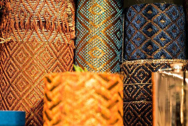 Cestas tejidas de colores con patrones geométricos, apiladas y con detalles de brillo metálico.