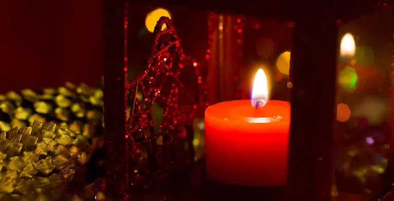 Red candle lit inside a lantern.