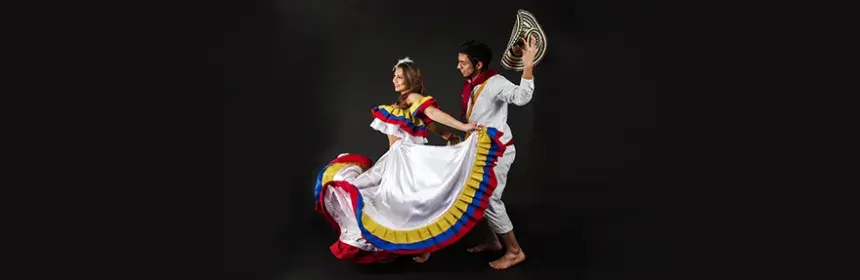 Pareja bailando cumbia colombiana con trajes tradicionales en fondo negro.