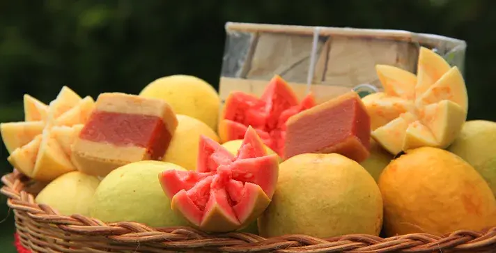 Canasta de mimbre con guayabas amarillas y bocadillos veleños rosados.