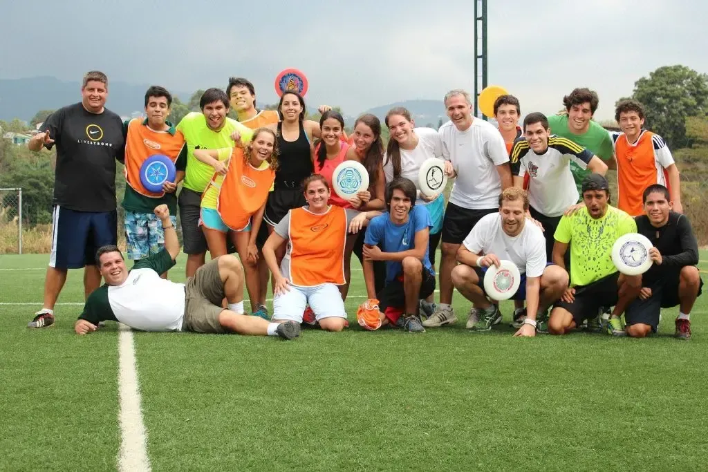 Grupo de jóvenes posando con discos en campo de ultimate.