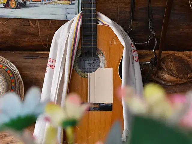 Guitarra acústica con tela blanca sobre fondo de madera rústica.