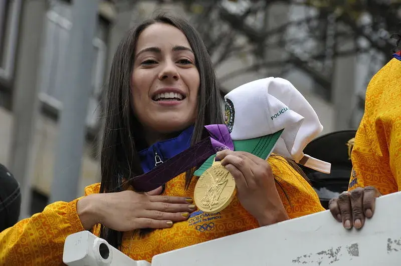 Descubre los logros de Mariana Pajón Mariana Pajón sonriendo y mostrando su medalla de oro olímpica.