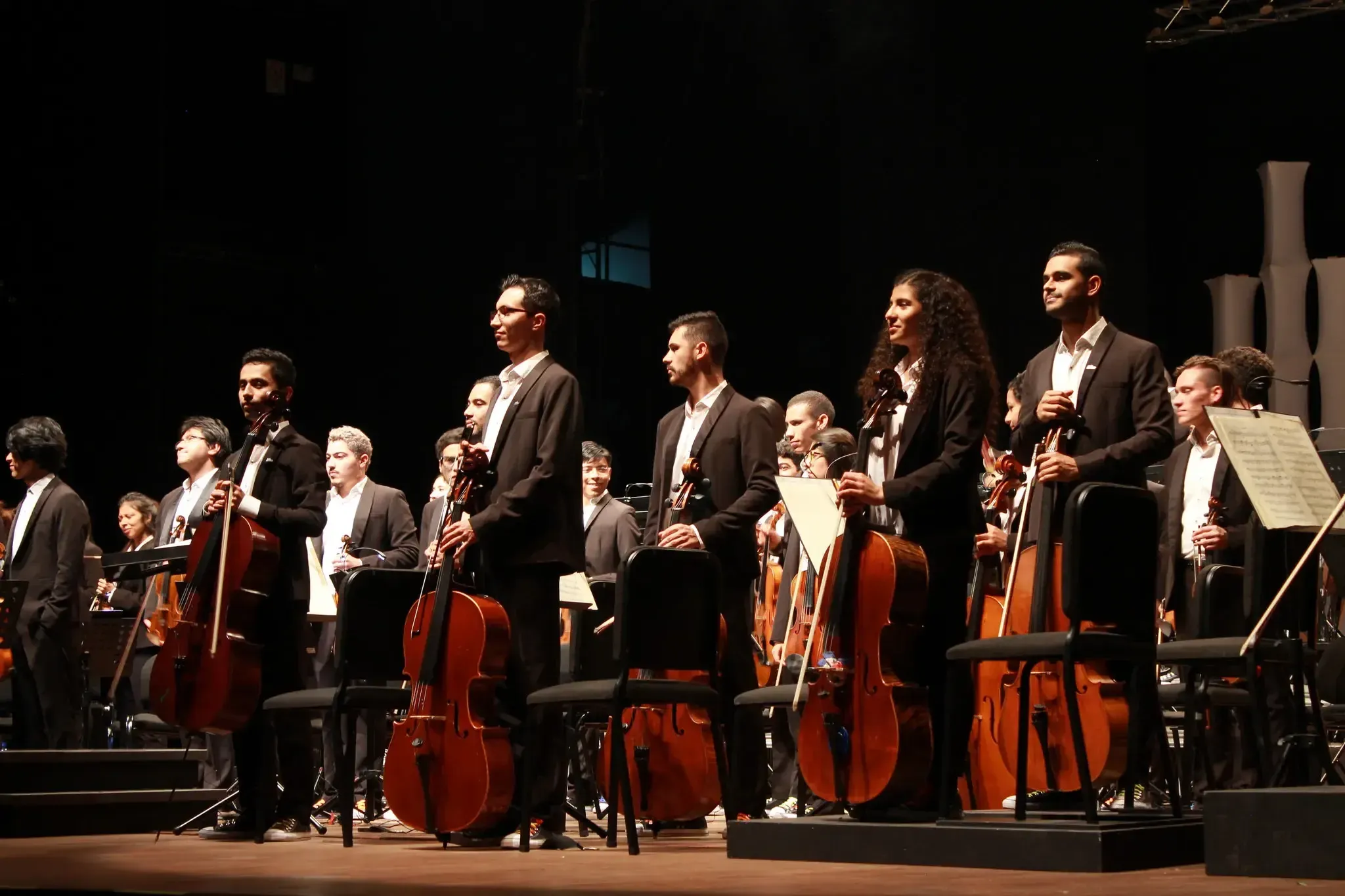 Músicos de orquesta de pie tras interpretación en vivo