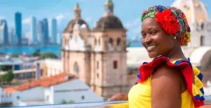 Palenquera sonriendo en Cartagena con la ciudad de fondo