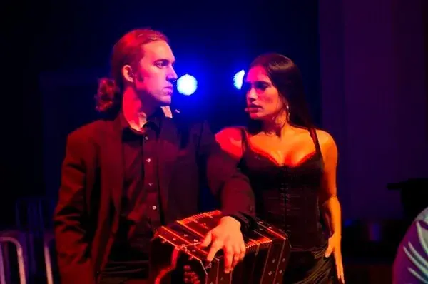 Pareja de tango con un bandoneón en un escenario. ¡Qué elegancia y pasión se sienten!
