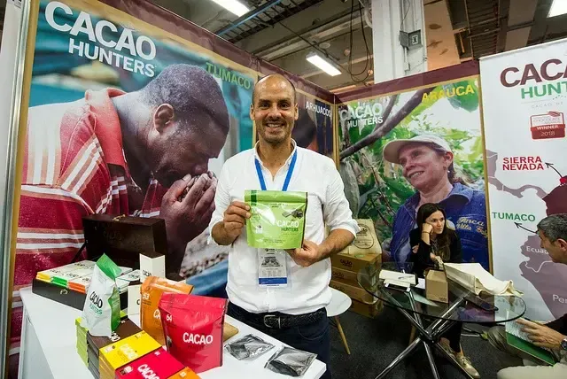 Hombre exhibe productos de cacao colombiano en feria comercial