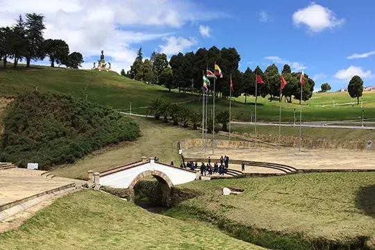 Puente de Boyacá blanco sobre un arroyo en un paisaje verde.