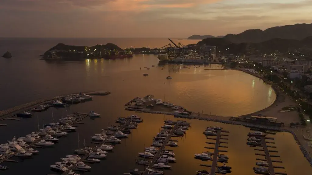 Vista aérea del puerto de Buenaventura al atardecer con barcos y montañas.