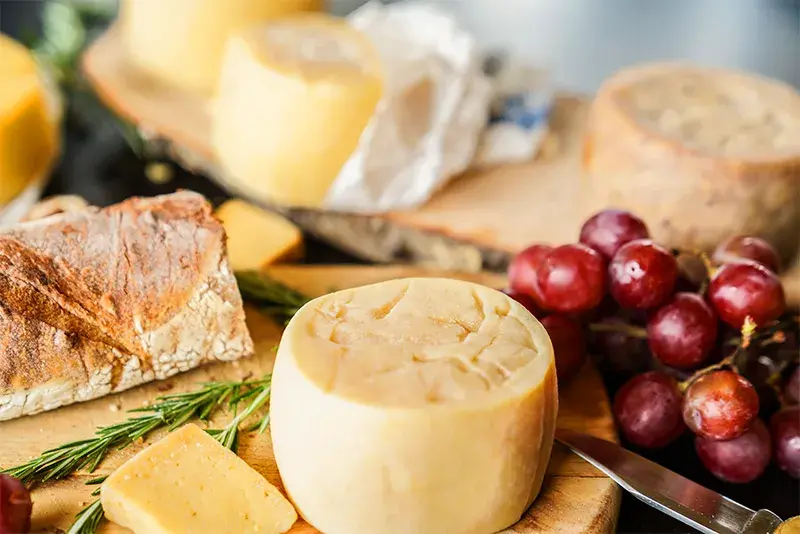 Queso Paipa en tabla de madera con uvas rojas y pan