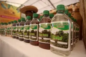 Filas de botellas de viche colombiano en una feria, con etiquetas verdes y tapas plásticas.