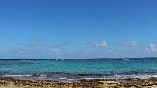 Vista del océano con cielo despejado y agua cristalina desde la orilla