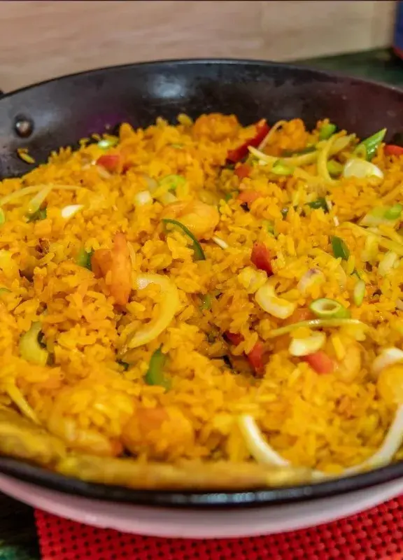 Arroz típico de la Costa Caribe de Colombia, servido en un sartén con vegetales y plátano frito Arroz típico de la Costa Caribe de Colombia, servido en un sartén con vegetales y plátano frito