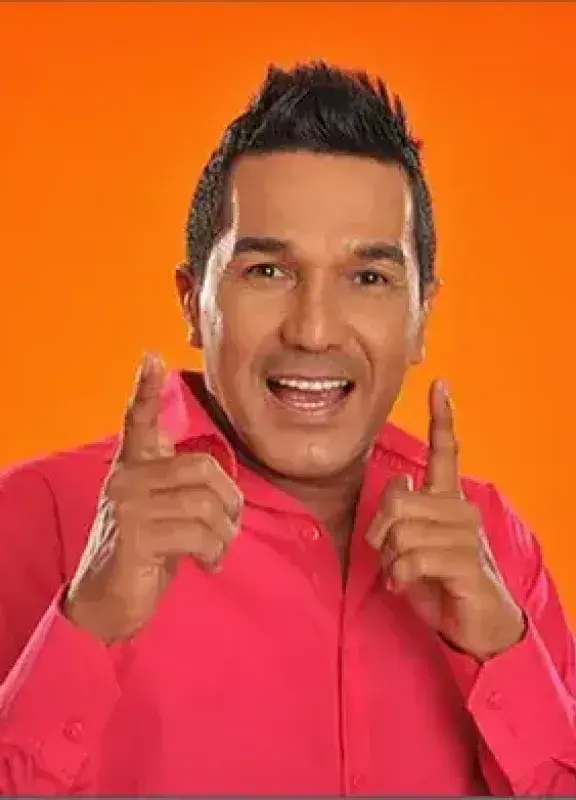 Hombre sonriente con camisa fucsia posando frente a fondo naranja Hombre sonriente con camisa fucsia posando frente a fondo naranja