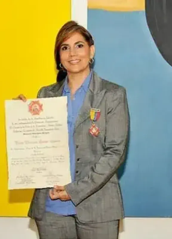Mujer recibiendo reconocimiento con diploma y medalla frente a pinturas coloridas Mujer recibiendo reconocimiento con diploma y medalla frente a pinturas coloridas