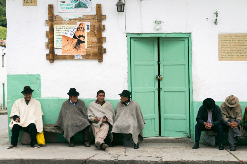 Hombres con ruana compartiendo en un pueblo colombiano.