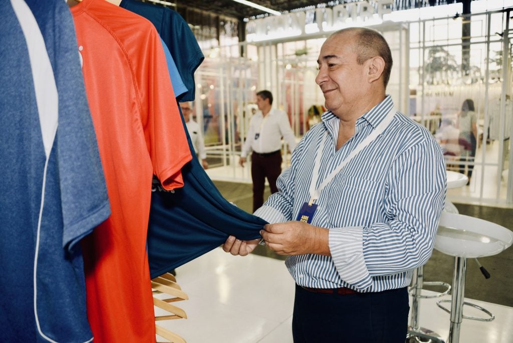 hombre tocando una prenda colgada con fondo de una convención, diseñadores colombianos, Colombiatex feria para el diseño colombiano