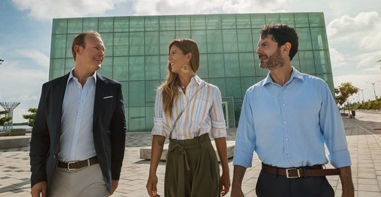 Tres personas caminando y sonriendo con fondo de edificio atras, oportunidades de negocio en Colombia, estudio de oxford