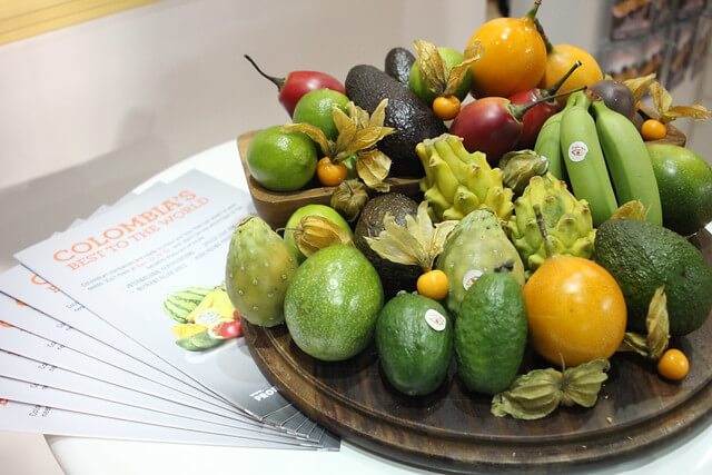 frutas sobre tabla que están en mesa blanca como pitaya, Feijoa, guayaba, platano, tomate de arbol, recetas de jugos naturales
