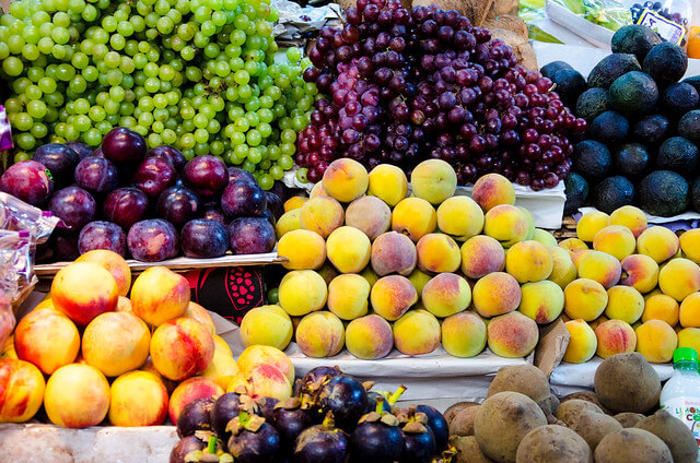 plaza de mercado con Frutas y verduras colombianas, melón, durazno, uvas, recetas de jugos naturales