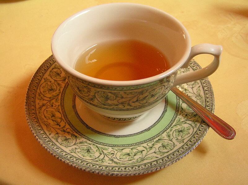 Plato sobre mesa color naranja con cuchara de lado y un Té de hierbas, remedios caseros, medicina alternativa, productos naturales