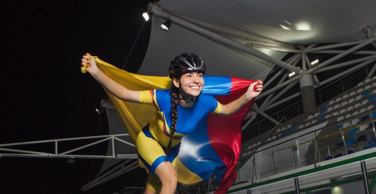 Deportistas colombianos llevando con orgullo la bandera de Colombia en un estadio