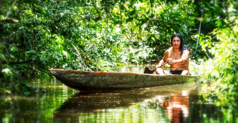 Colombian indigenous in traditional canoe made of a single tree