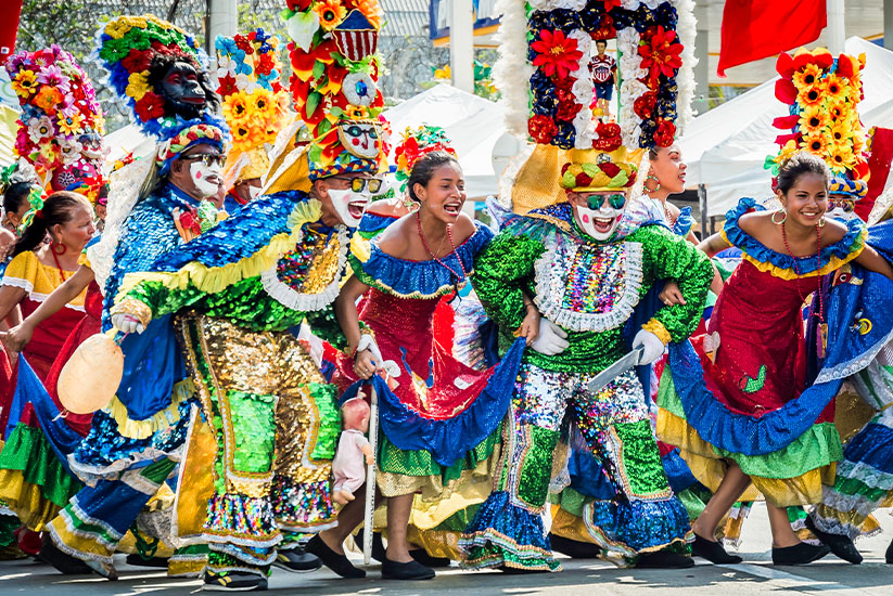 Mujeres y hombres disfrazados bailando en el Carnaval de Barranquilla